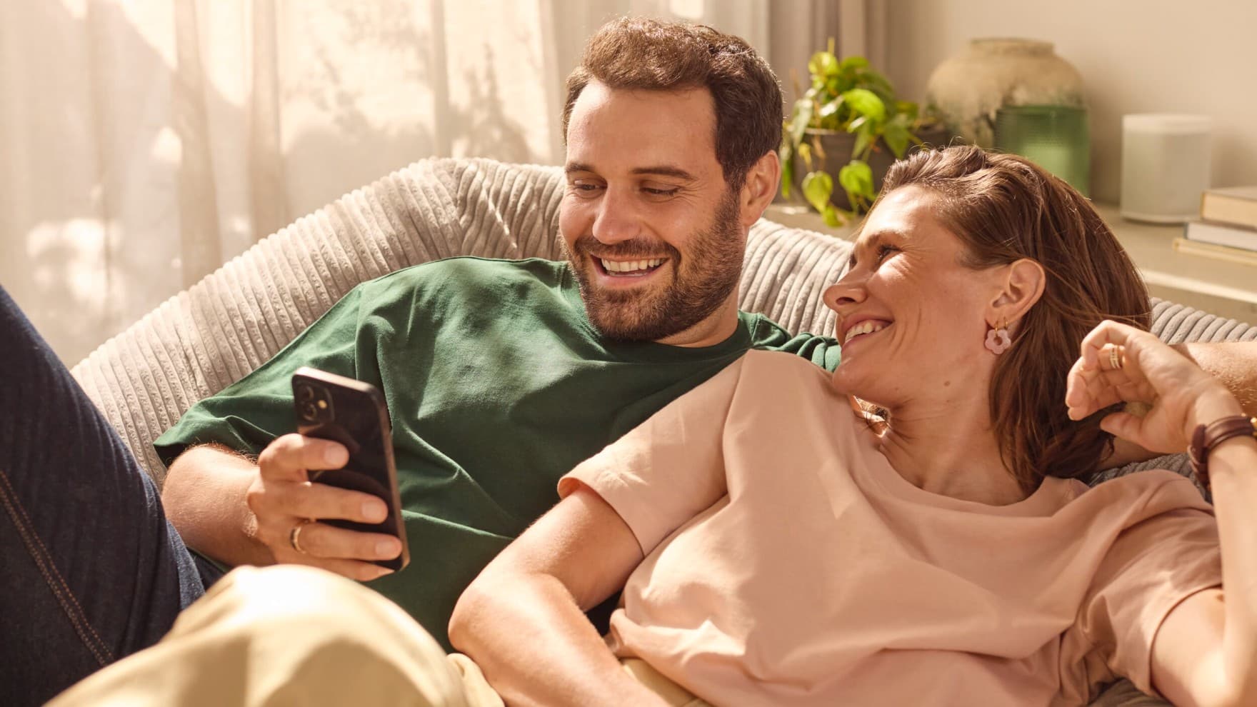 Stel zit op de bank en kijkt naar een telefoon