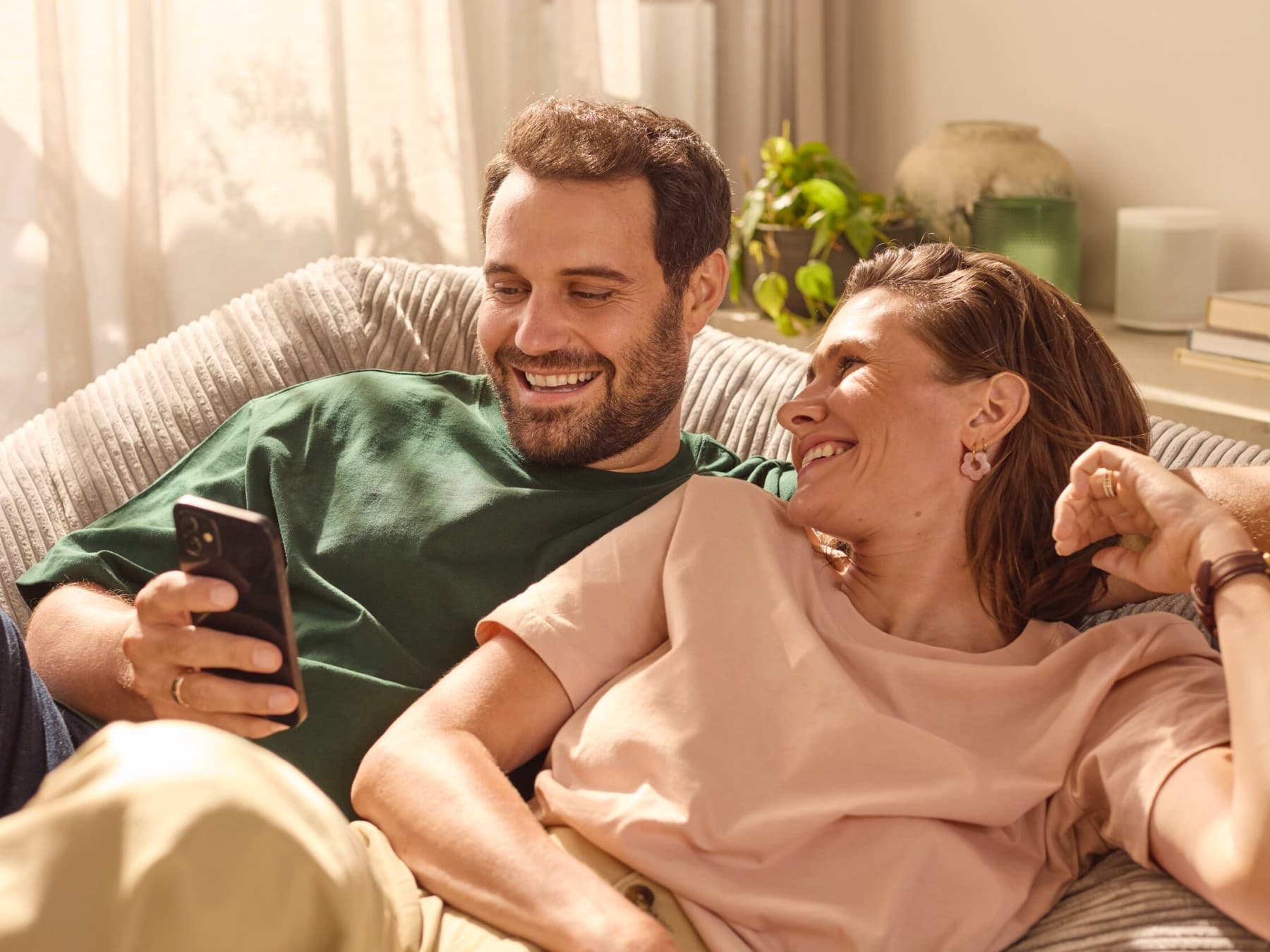 Stel zit op de bank en controleert het energieverbruik via een app