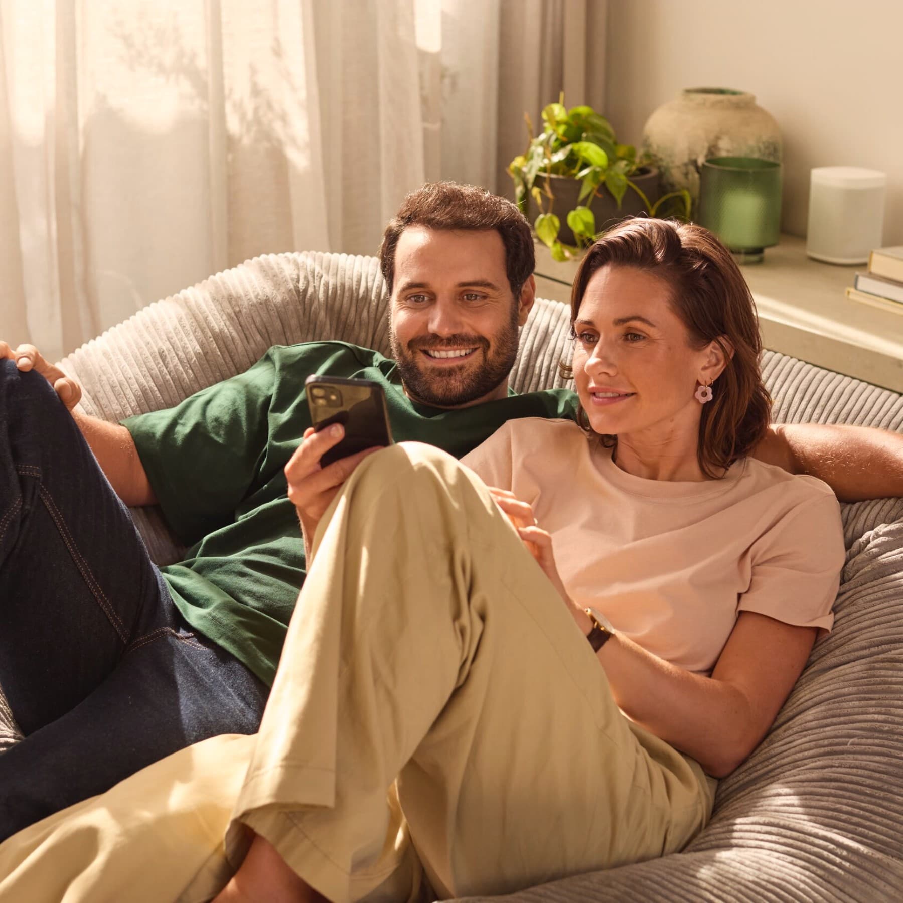 Een stel dat naast elkaar zit en op hun telefoon kijkt.