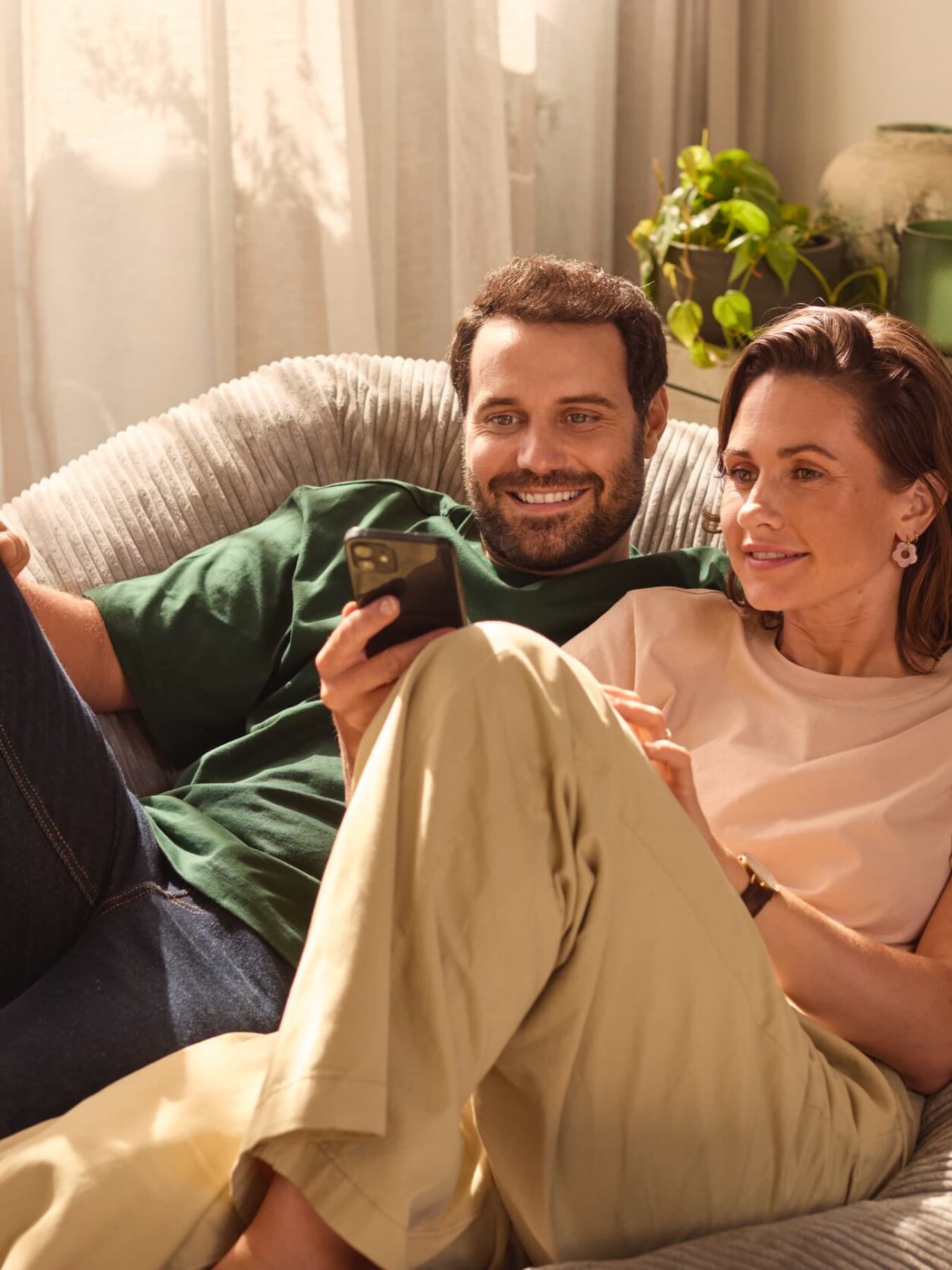 Stel zit op een bank en kijkt naar een smartphone