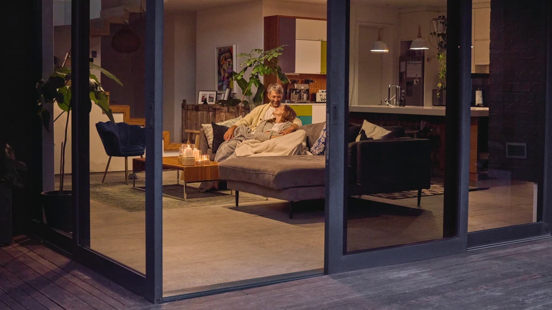 Stel zittend op de bank met de patiodeur open