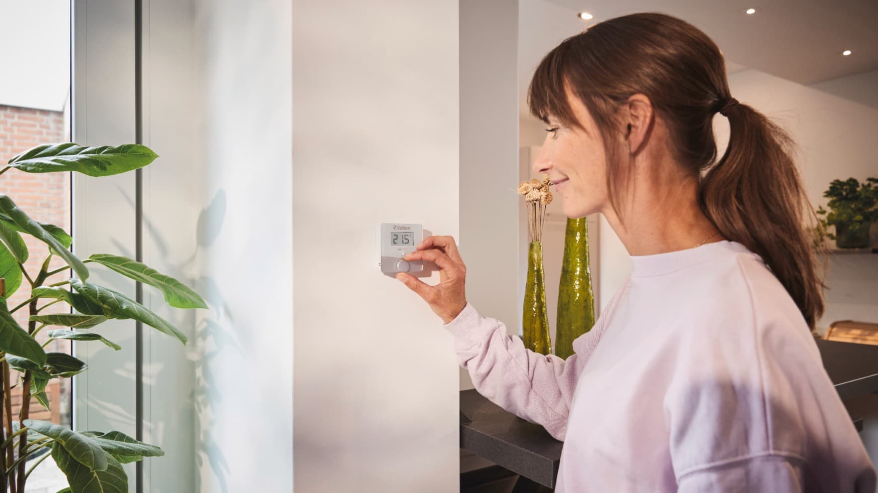 Vrouw die de Vaillant-thermostaat sensoROOM gebruikt