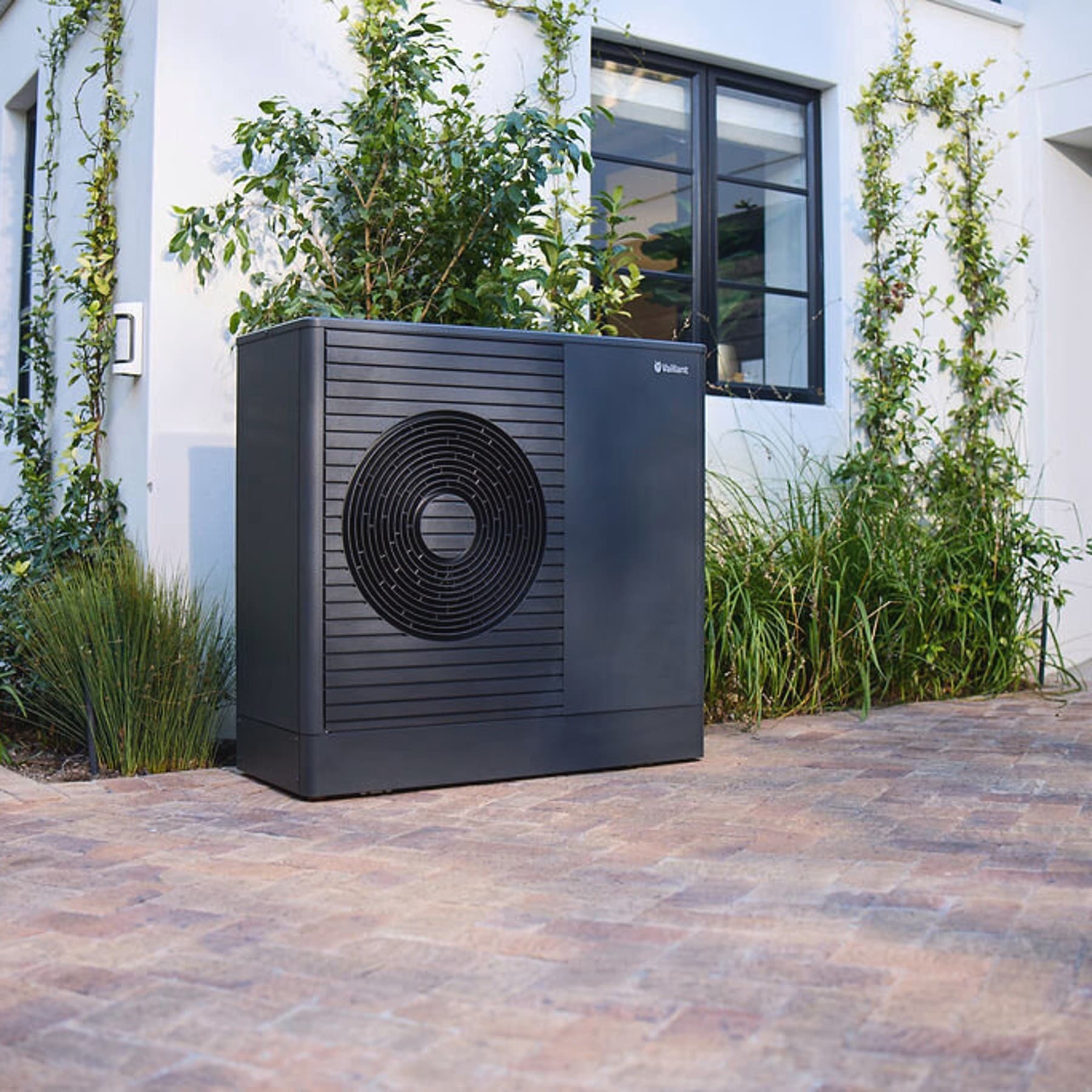 Donkere Vaillant aroTHERM plus warmtepomp in de voortuin van een huis