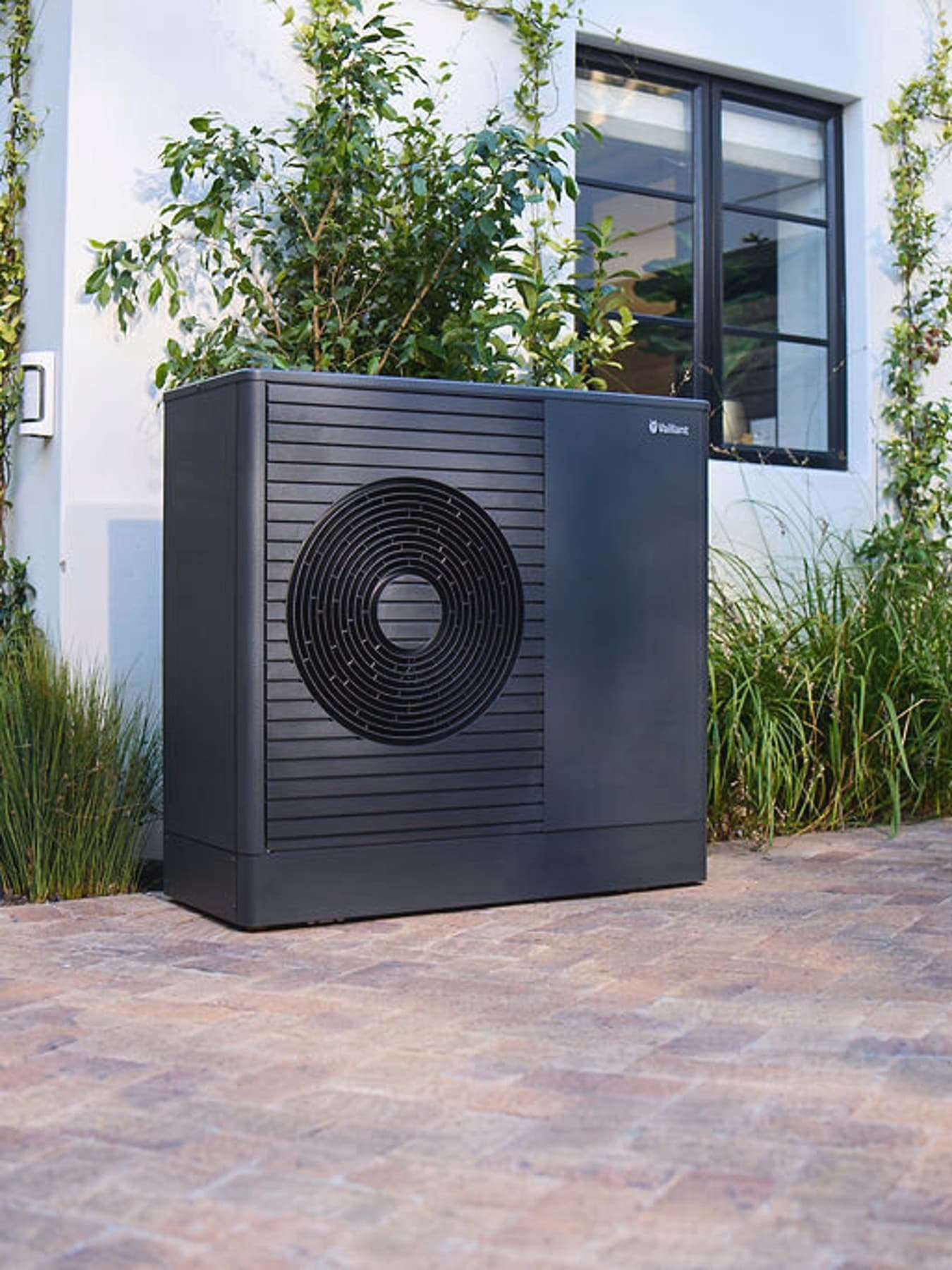 Donkere Vaillant aroTHERM plus warmtepomp in de voortuin van een huis