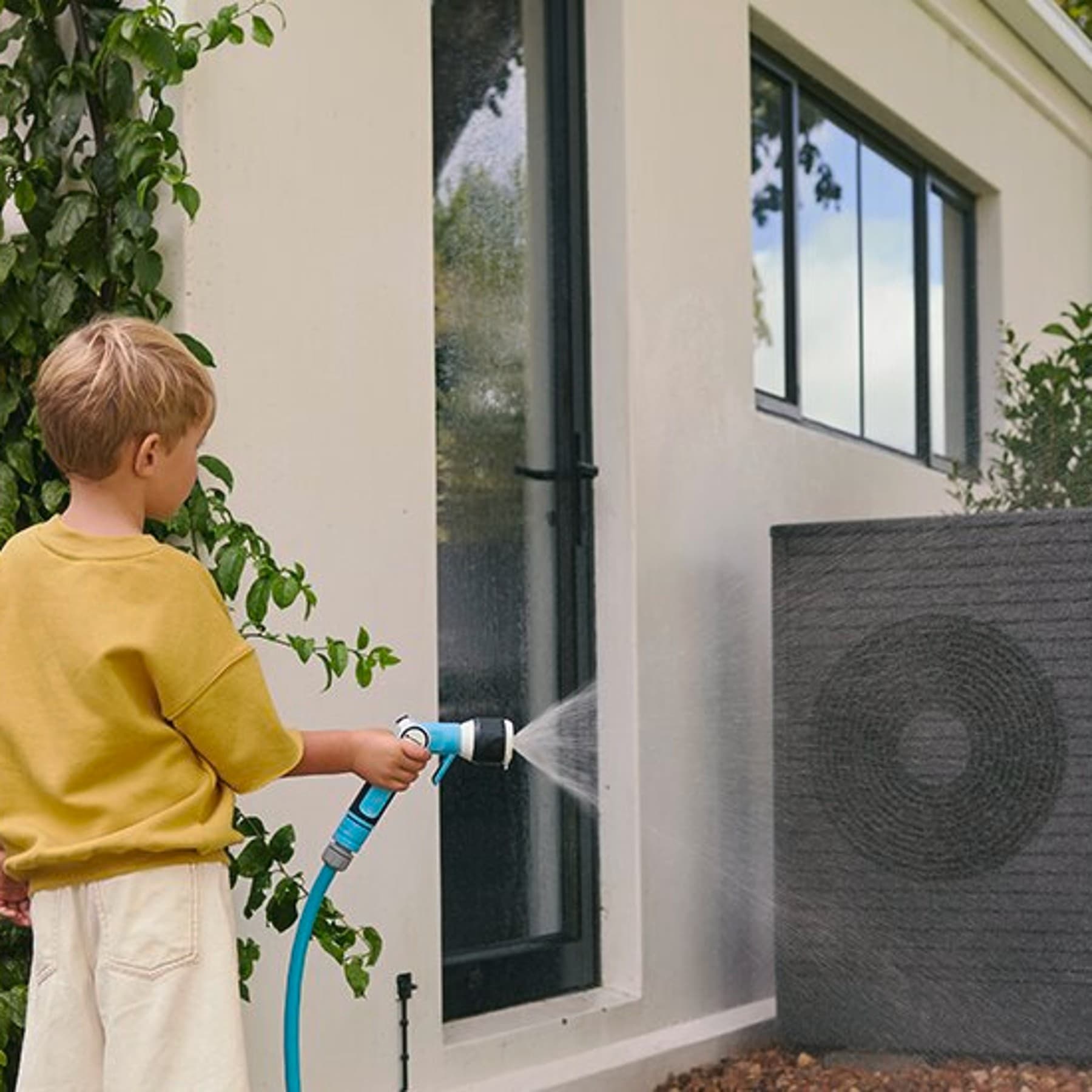 Kind met tuinslang voor warmtepomp