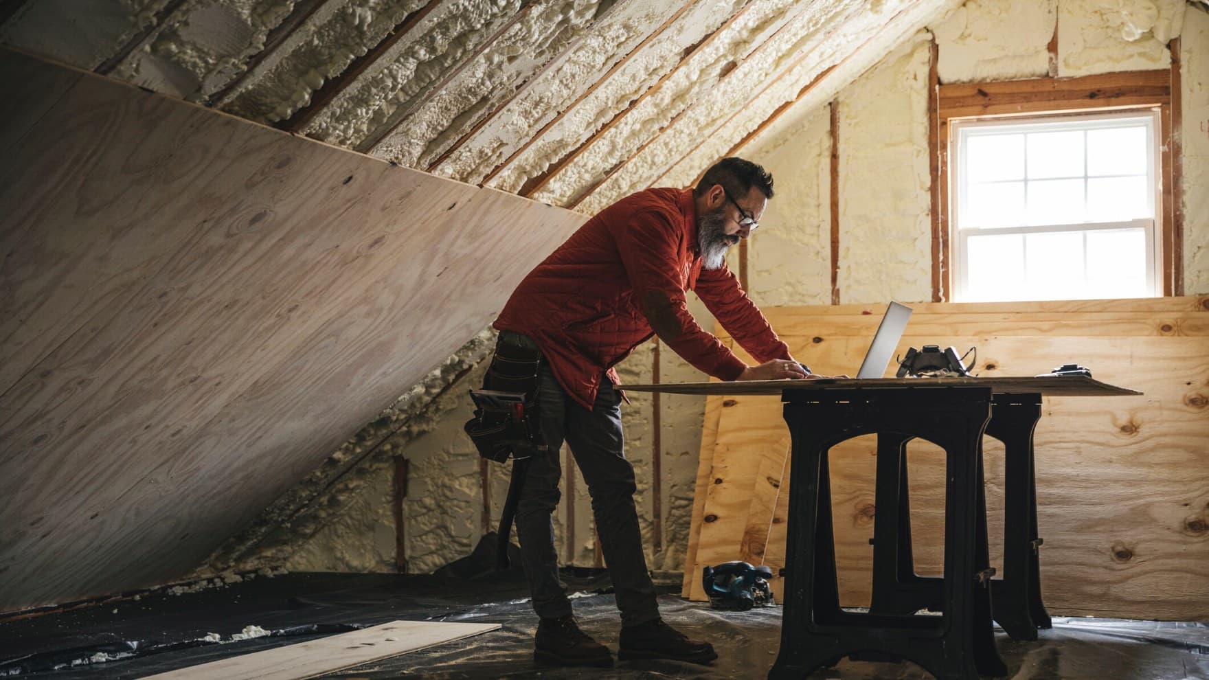 Timmerman kijkt naar laptop tijdens het isoleren van een huis
