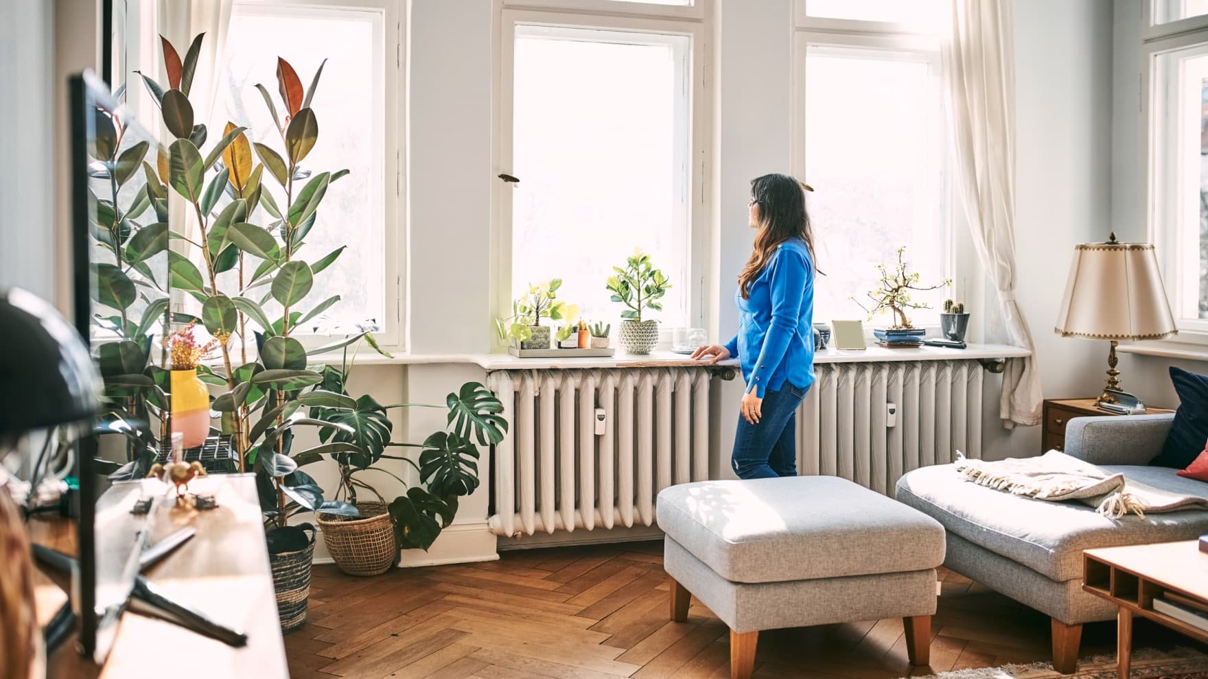 Vrouw die in de woonkamer voor het raam staat en naar buiten kijkt