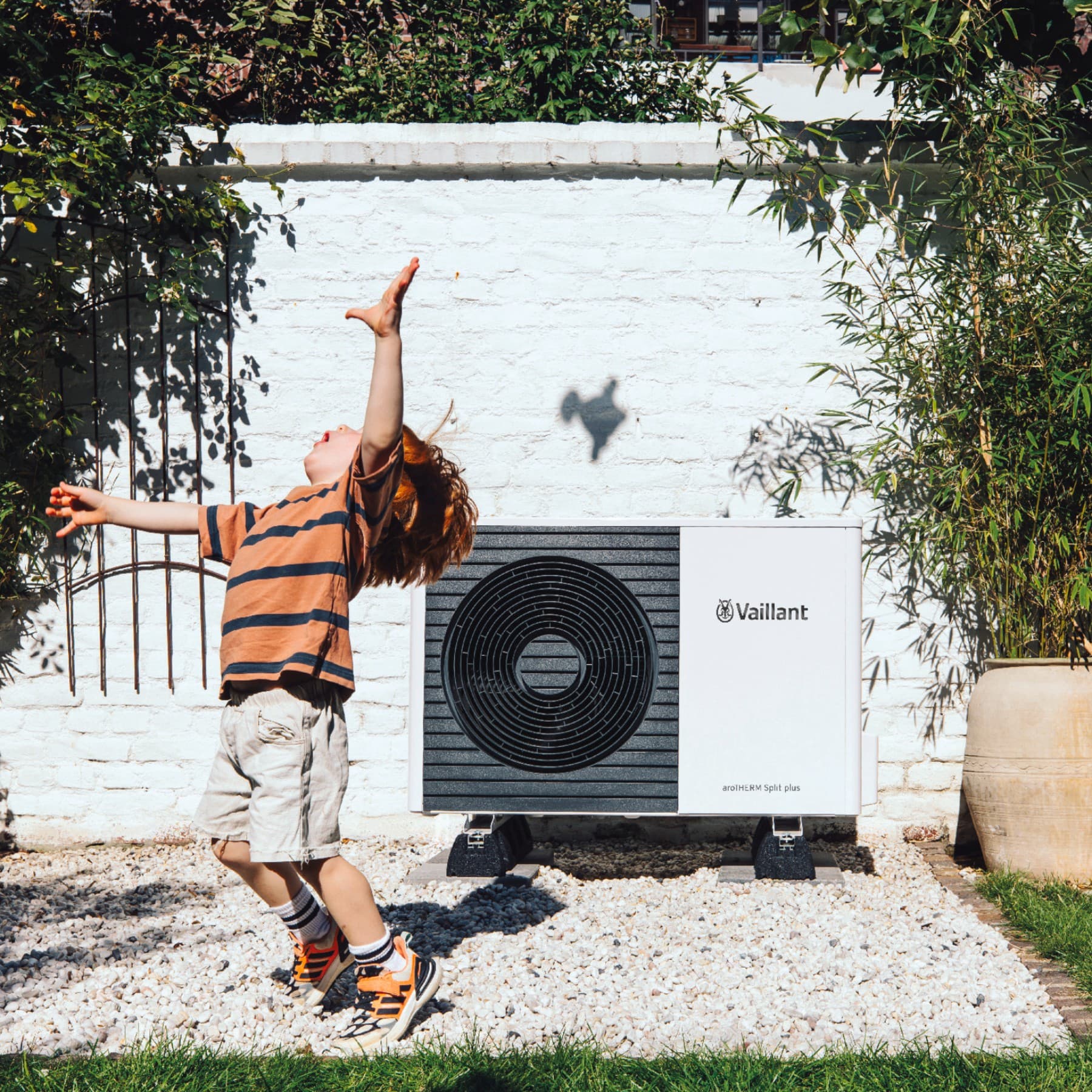 Kind speelt voor een warmtepomp in de tuin