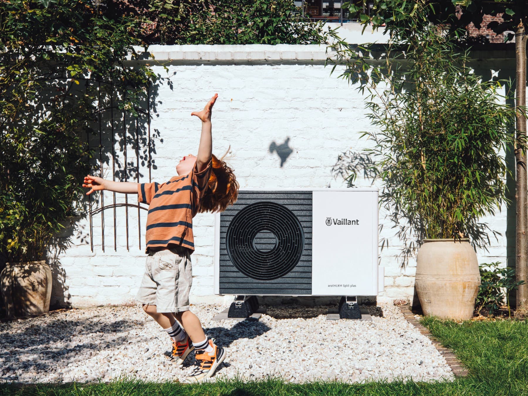 Kind speelt met een bal voor een warmtepomp