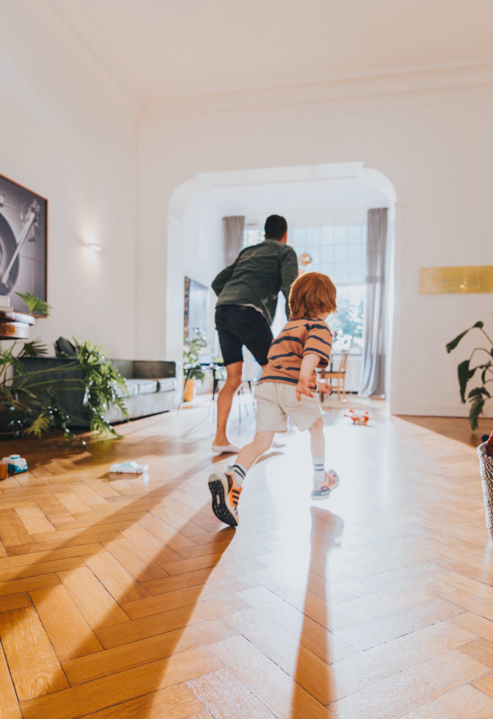 Man die met zijn kind in de woonkamer speelt.