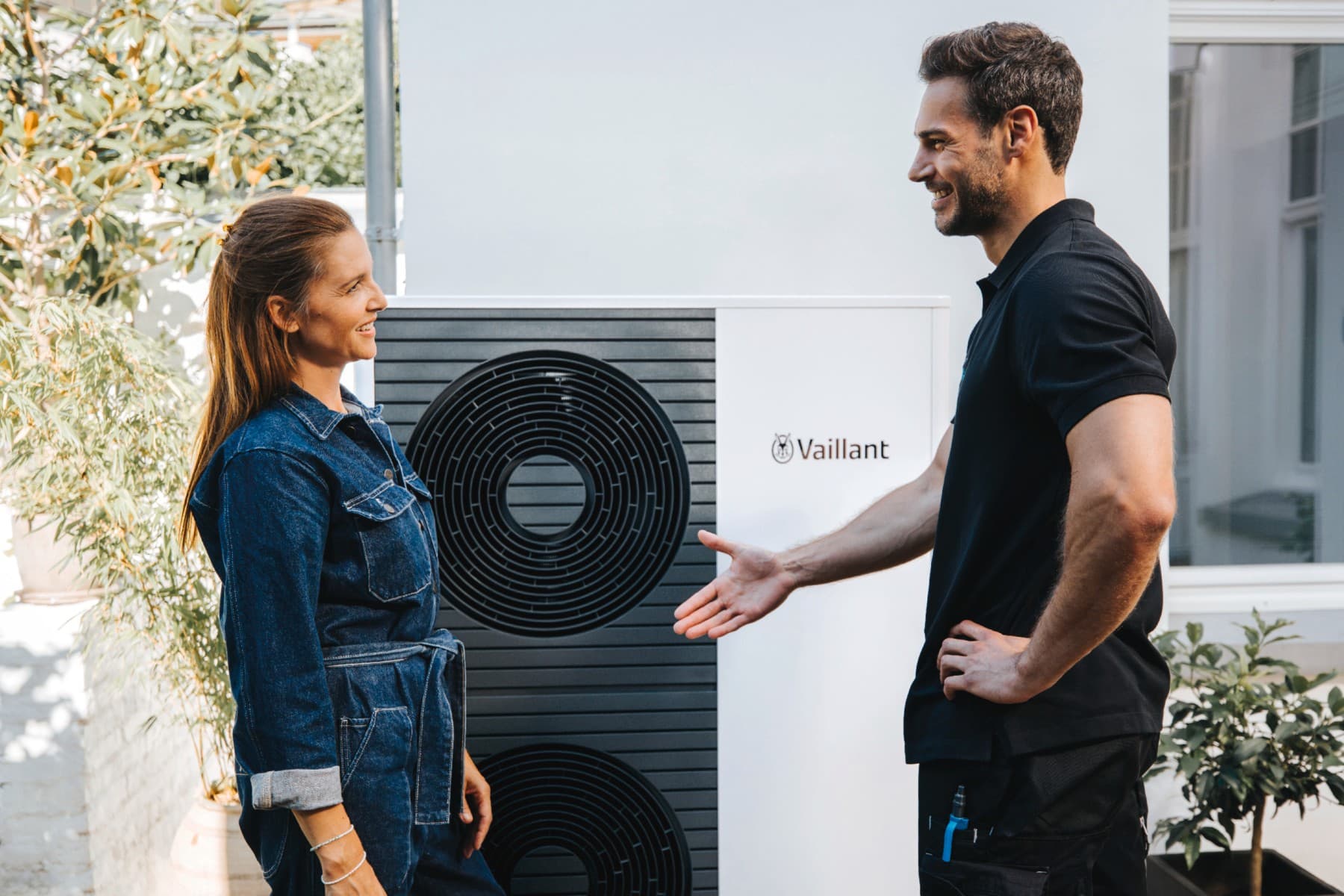 Een vrouw en een monteur van Vaillant die elkaar de hand schudden voor een warmtepomp