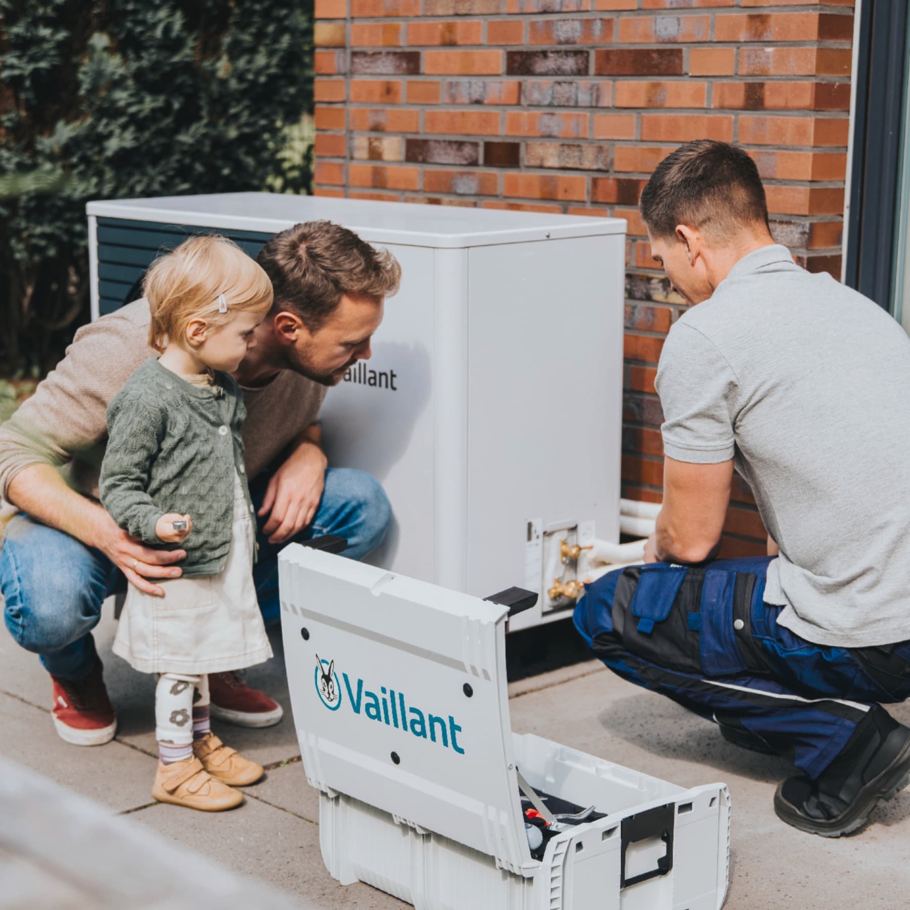 Een meisje en haar vader kijken toe hoe een installateur een warmtepomp installeert.