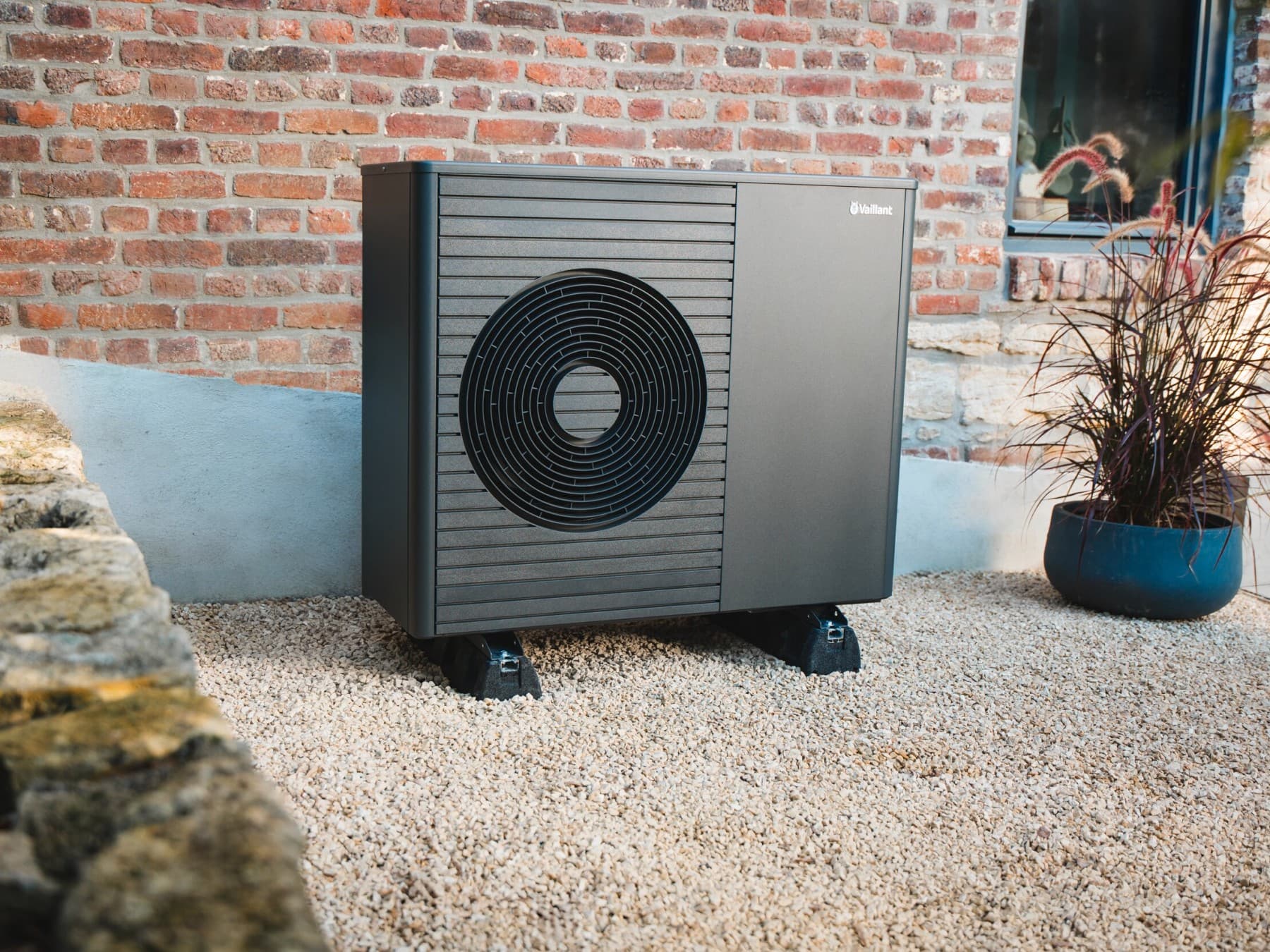 Buitenwarmtepomp geplaatst voor de muur van het huis.