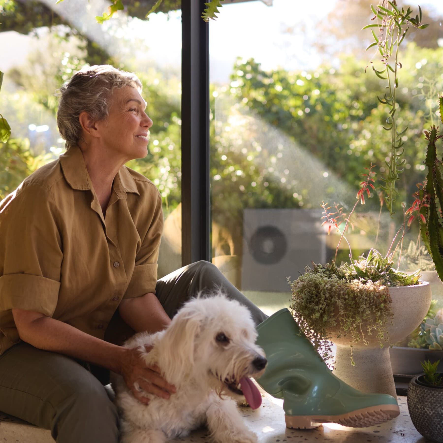 Vrouw zit met haar hond bij het raam