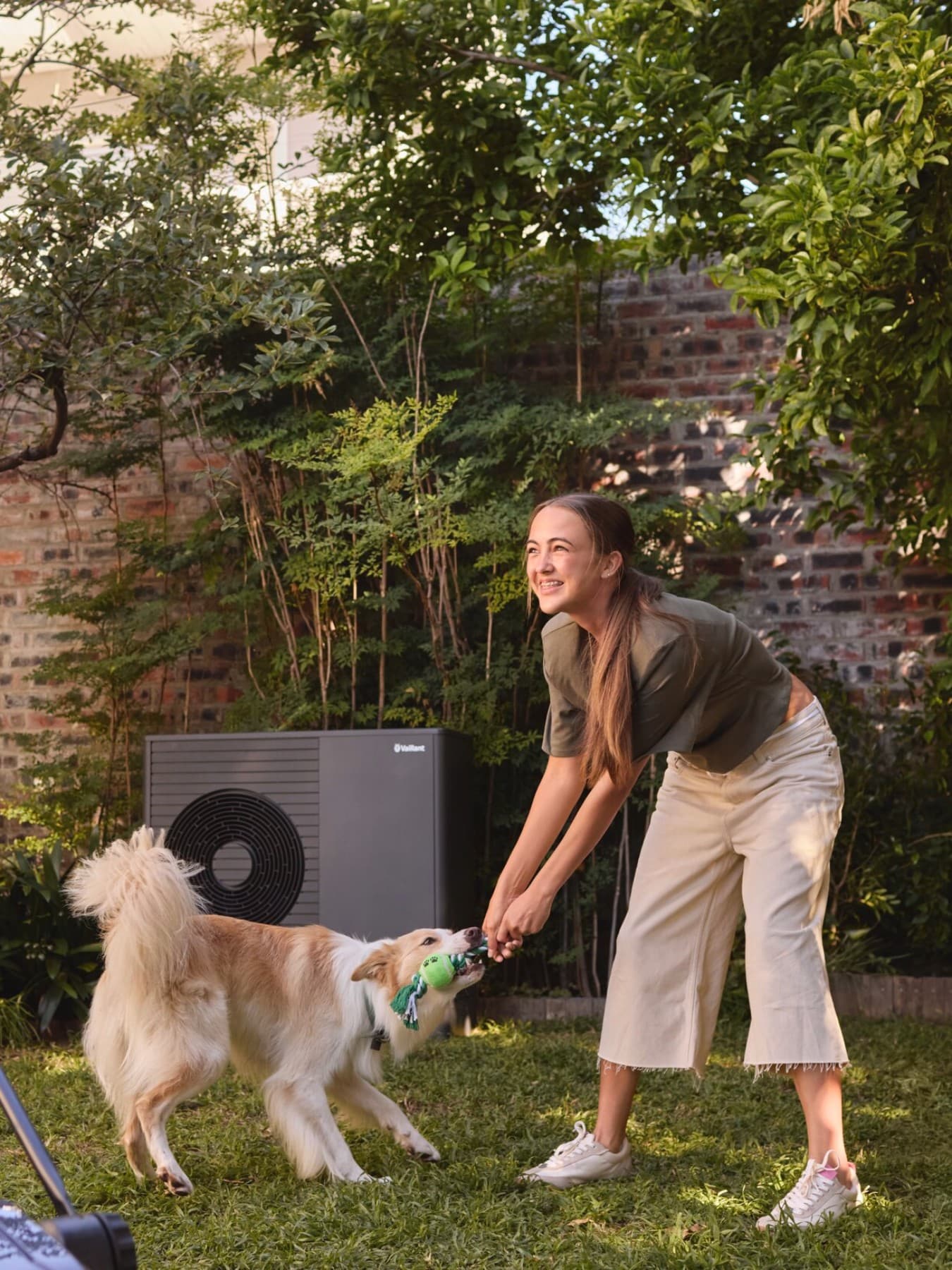 Vader en dochter in de tuin met een warmtepomp op de achtergrond