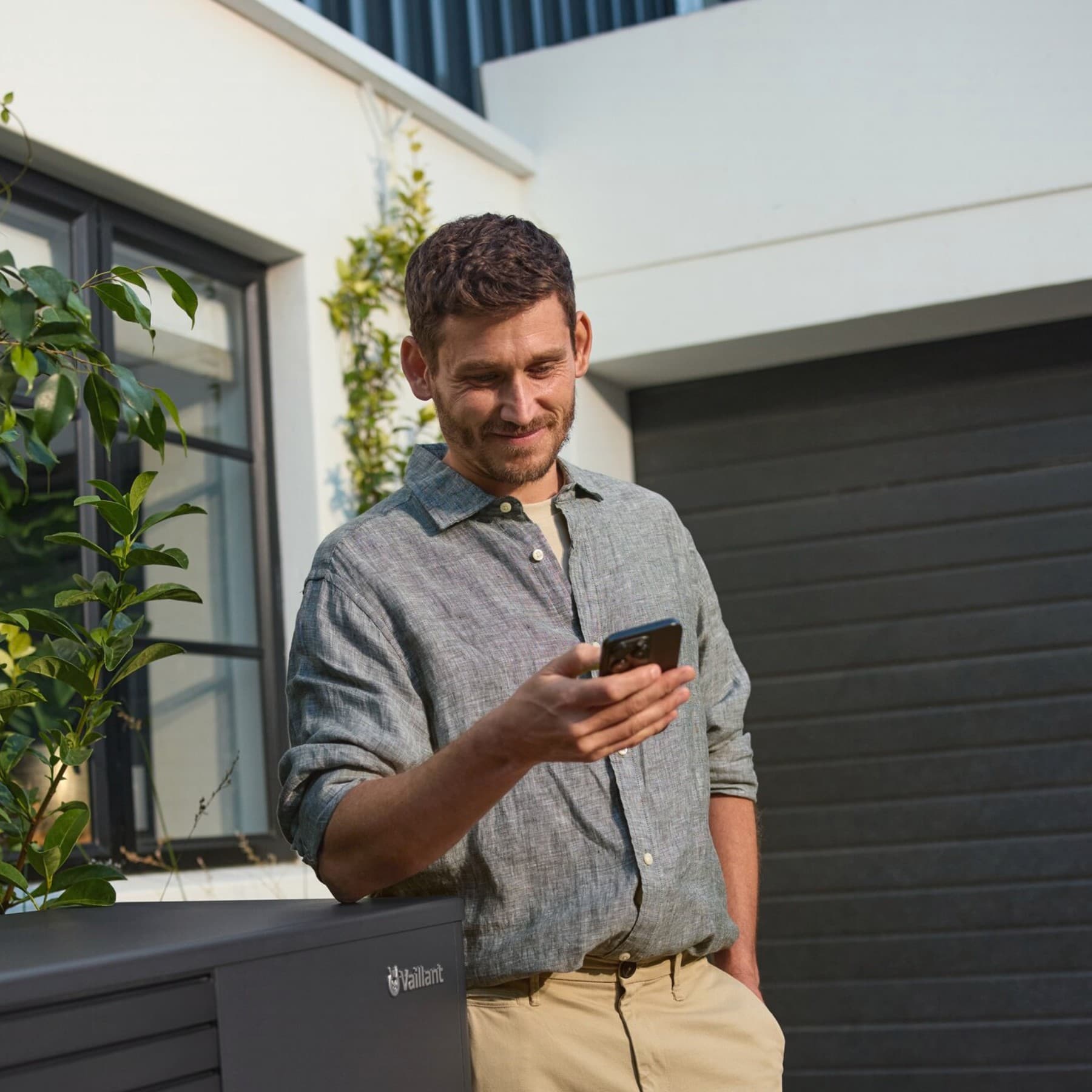Man in tuin van een woning met zonnepanelen en warmtepomp