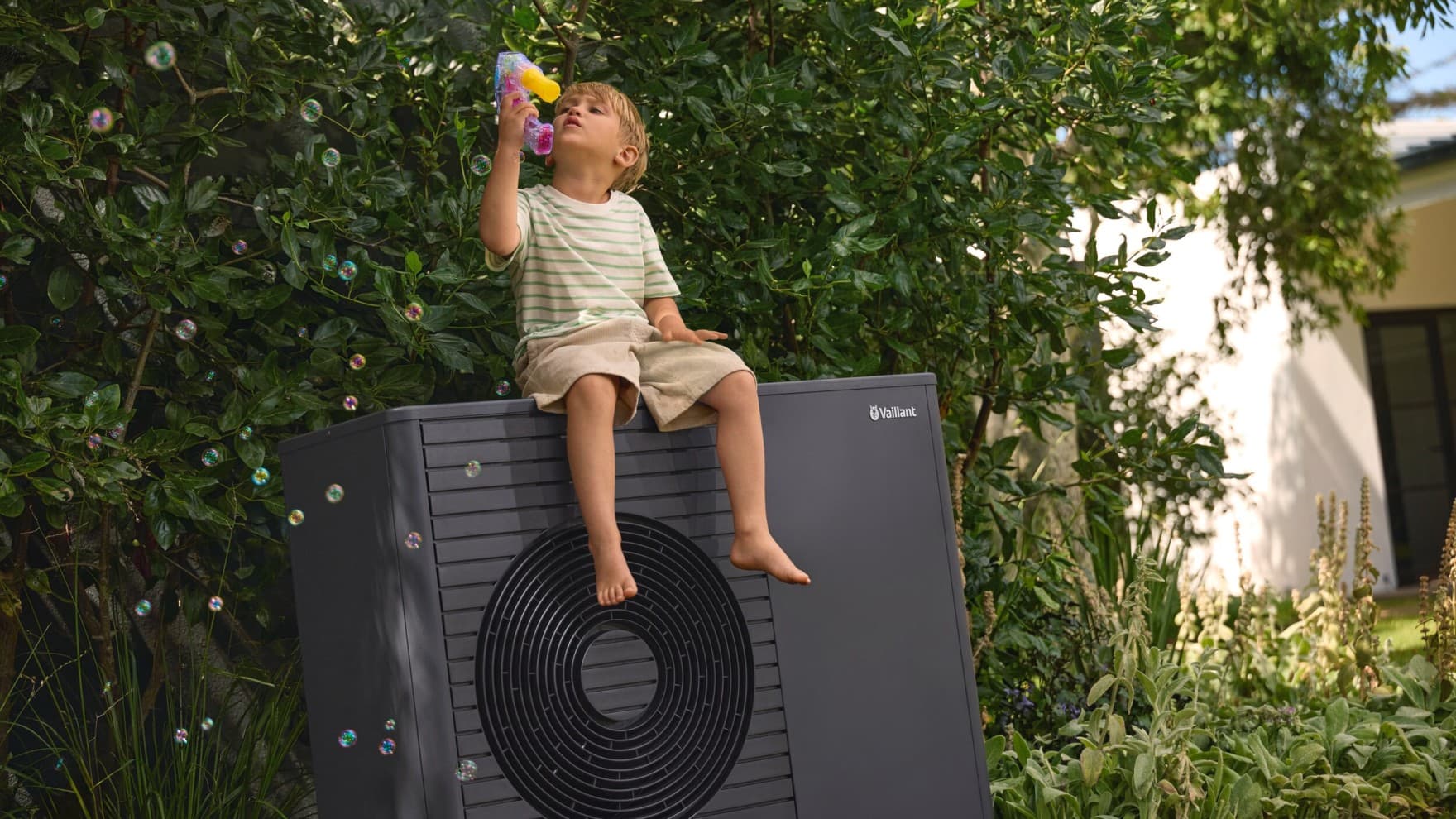 kind dat bellen blaast terwijl het op een warmtepomp in de tuin zit