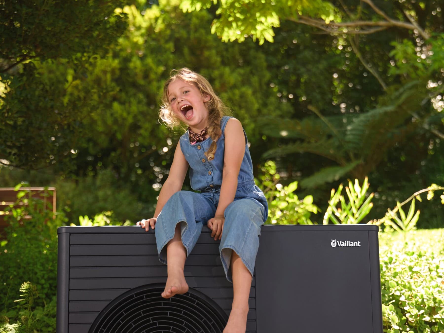 Een klein meisje zit op een warmtepomp.