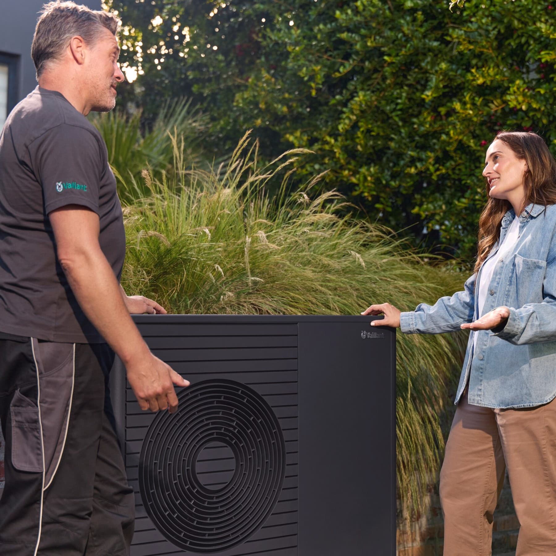 Installateur van warmtepompen en huiseigenaar in gesprek naast een warmtepomp