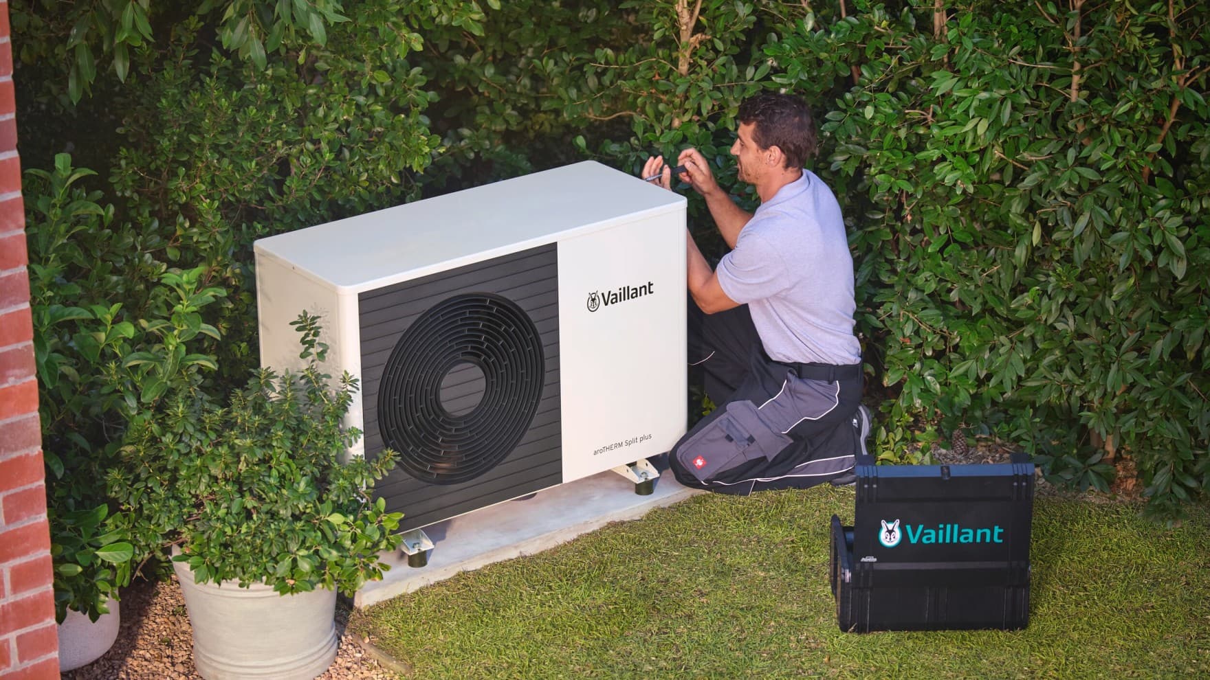 Een installateur controleert een warmtepomp met een gereedschap.