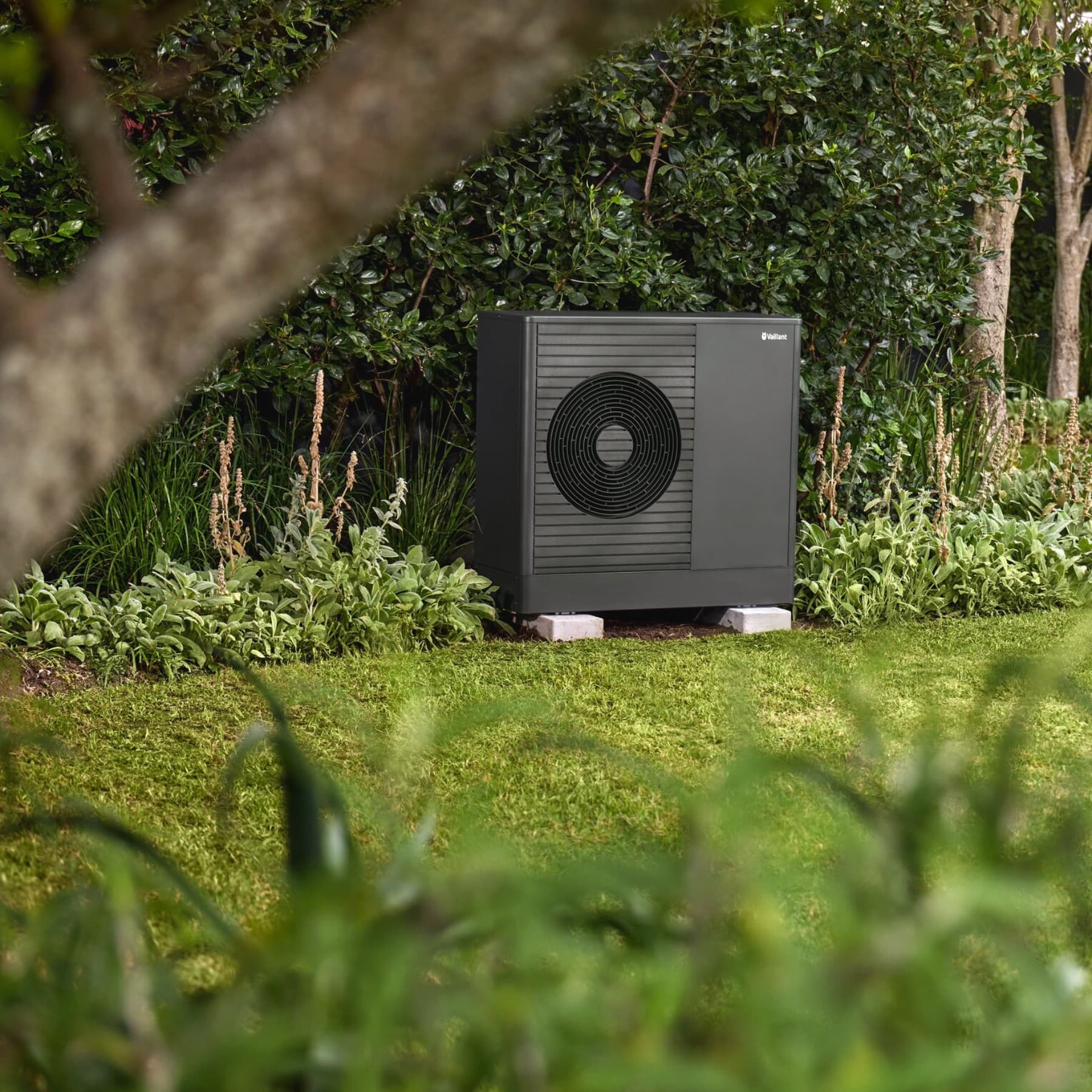 Een Vaillant-warmtepomp in de tuin voor een huis.