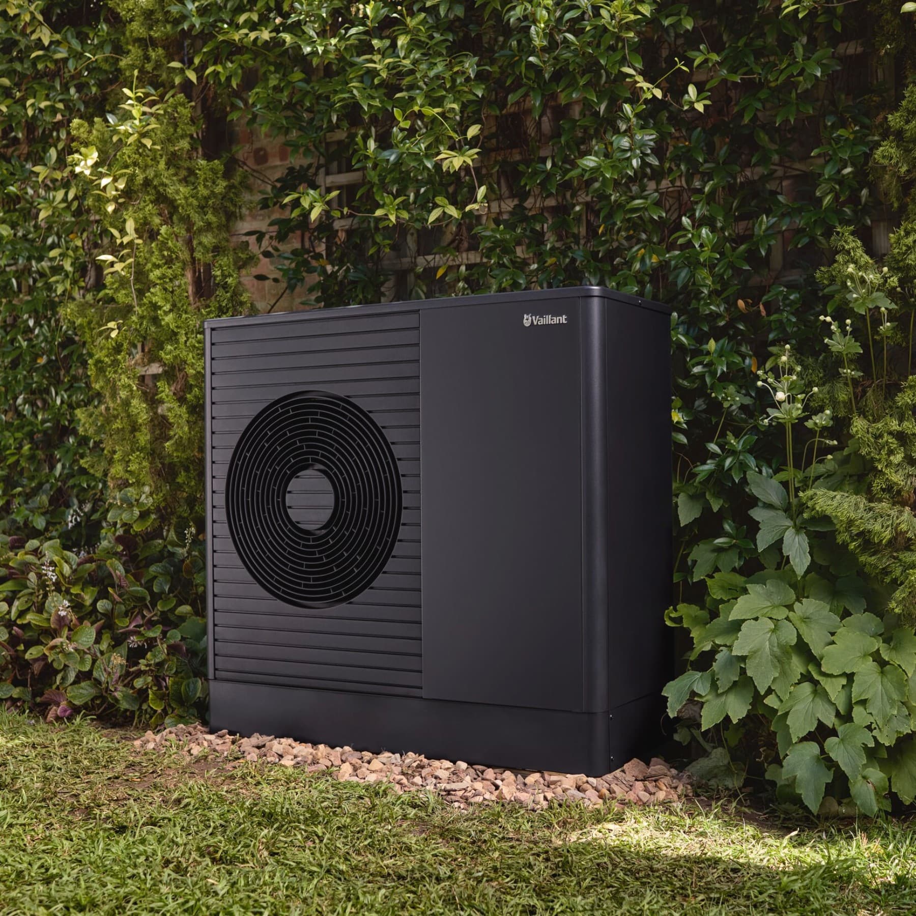 Warmtepomp buitenunit, staande voor een muur in een tuin