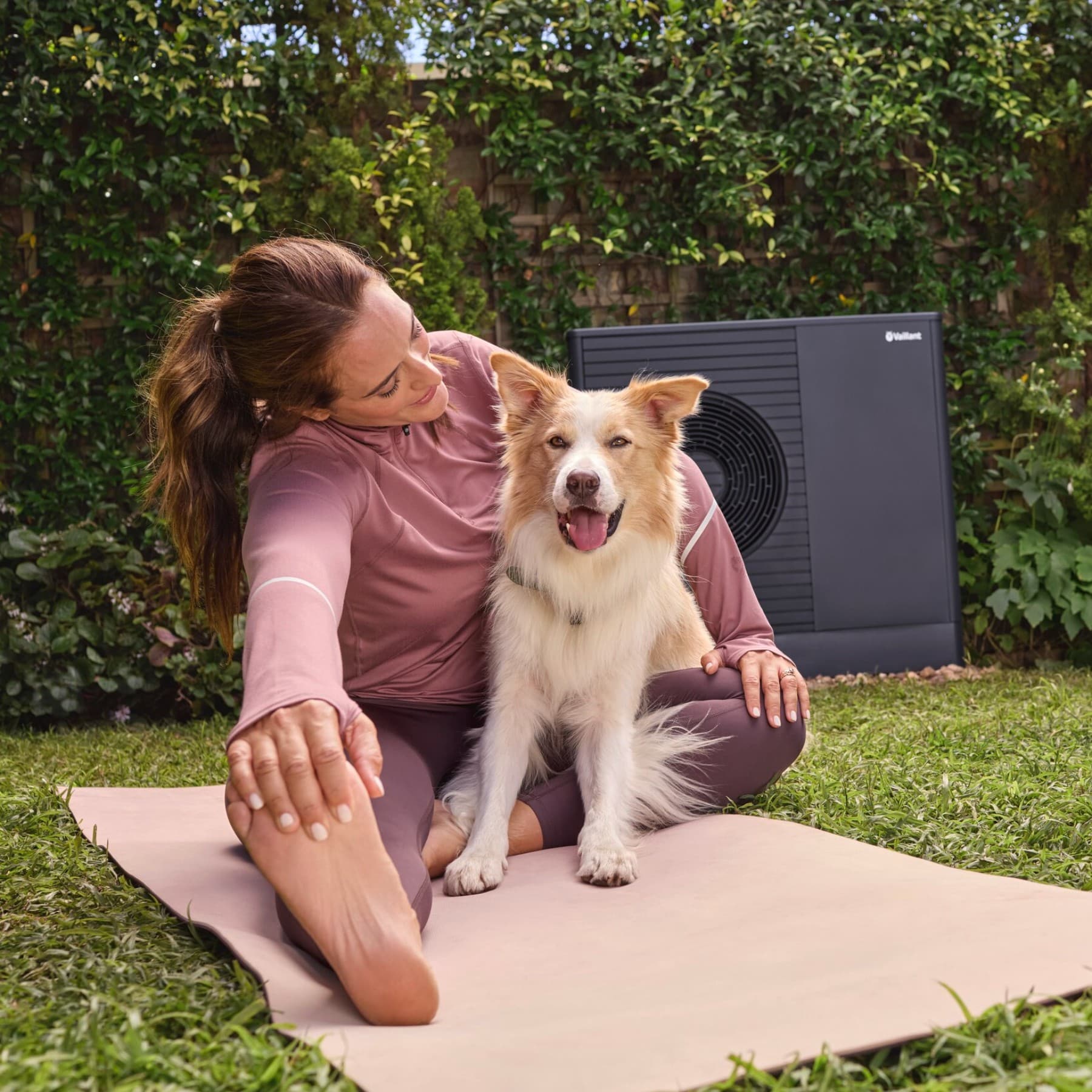 Vrouw en hond zitten voor een warmtepomp