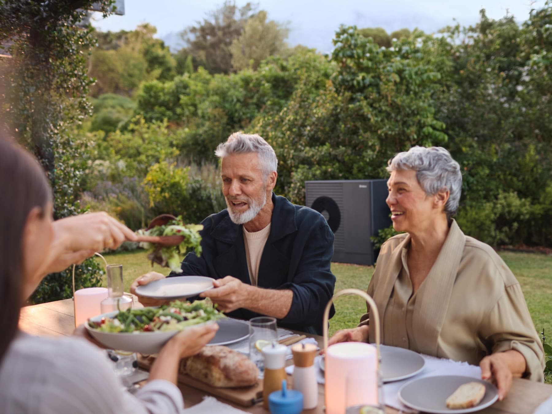 Mensen die in hun tuin dineren en genieten van de stilte van hun warmtepomp.