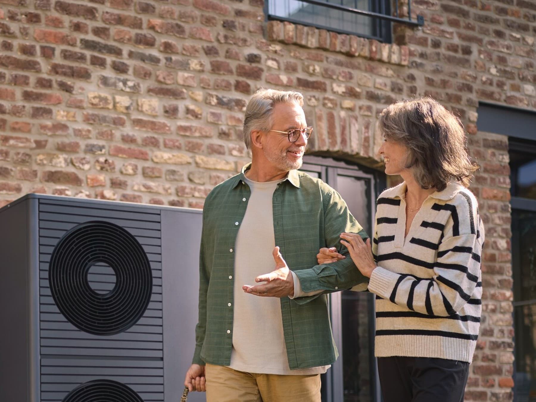 Een echtpaar loopt buiten hun huis voor een warmtepomp.