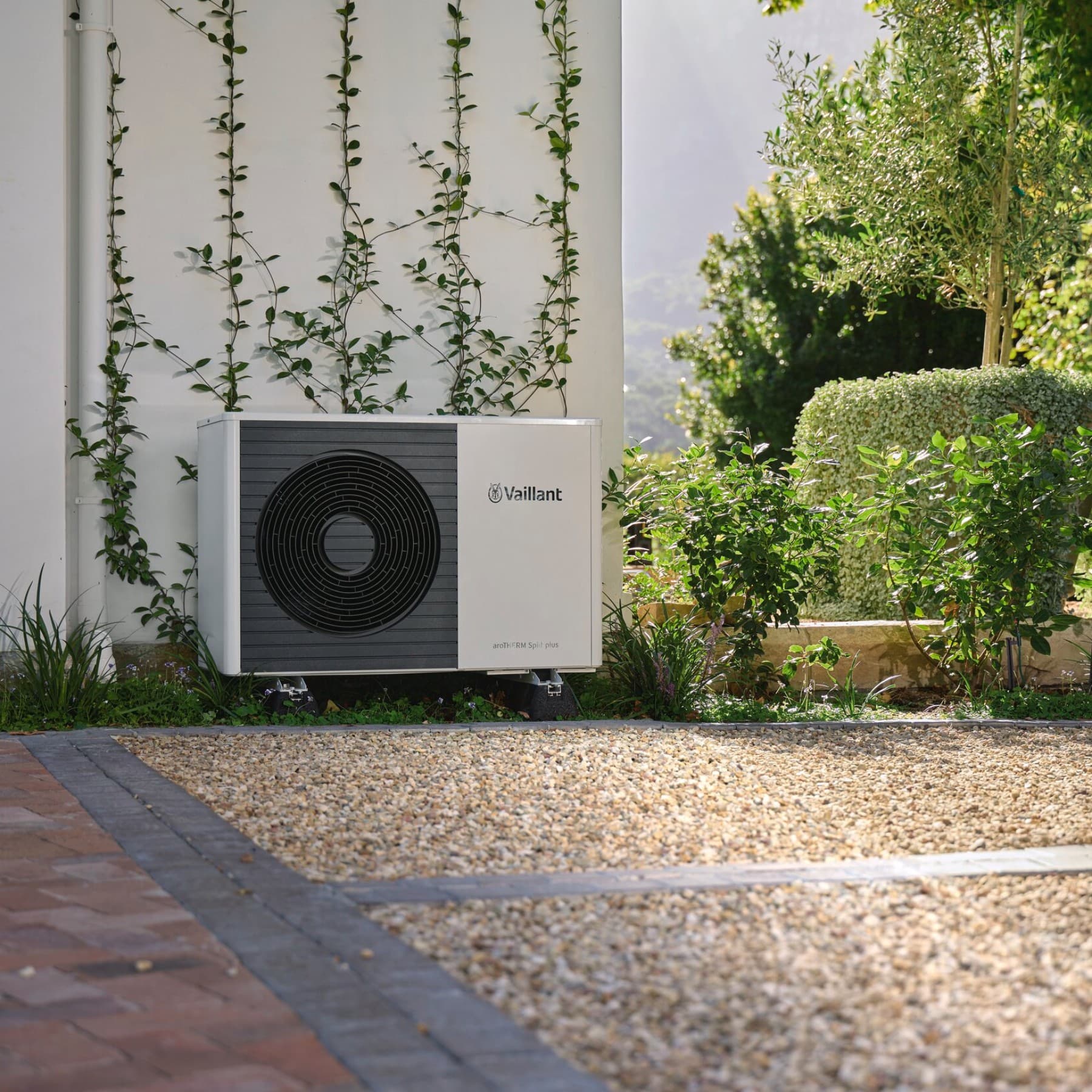 Warmtepomp buitenunit, staande voor een muur in een tuin