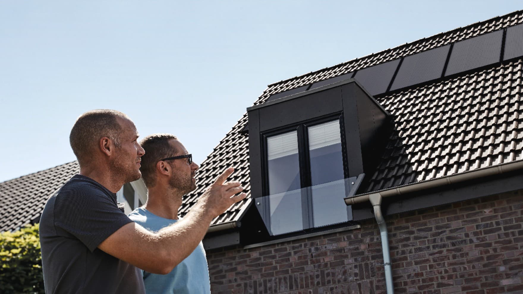 Vakmensen en de huiseigenaar inspecteren het gerenoveerde dak.