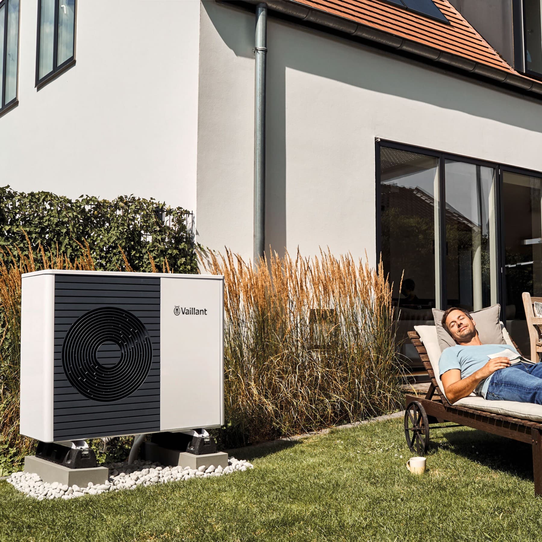 Man in tuin van een woning met zonnepanelen en warmtepomp