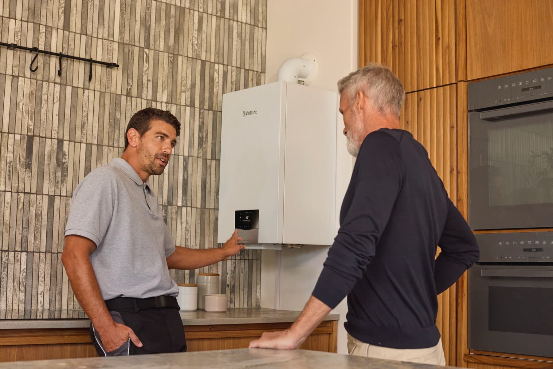 Installateur wijst naar boiler en geeft uitleg aan een klant